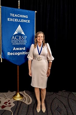Justyna Koc standing in front of ACBSP Award Banner