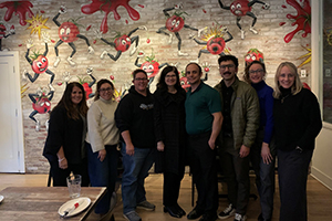 Photo of President Moore and staff standing in front of a wall with an animate tomatoes