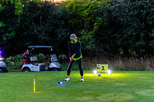 Woman teeing off in the dark