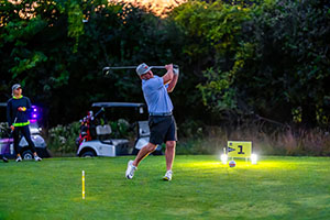 Guy teeing off in the dark
