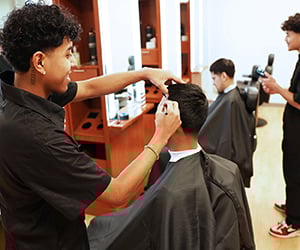 Student cutting hair of another student