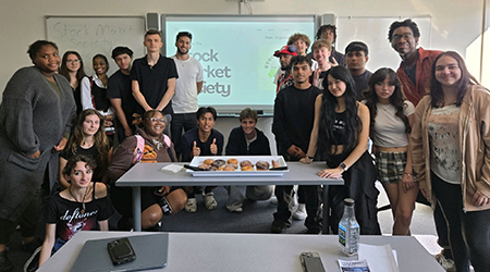 Photo of students gathered around a table with donuts