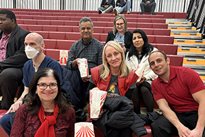 Photo of President Moore Sitting with staff on the gym bleachers