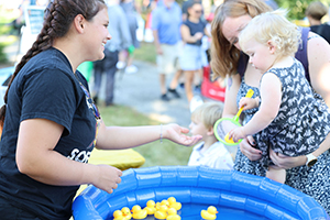 Photo of little girl and her mother pulling plastic duck from a pool