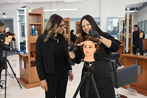 Photo of Instructor and student styling hair with a mannequin head